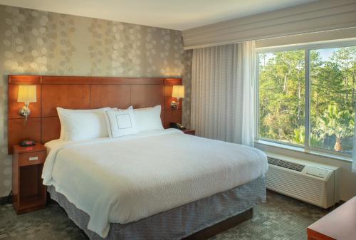 a bedroom with a large bed and a large window at Courtyard Jacksonville Orange Park in Orange Park