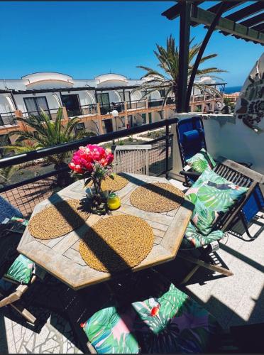 Apartamento BLUE OCEAN Complex Amaya Fuerteventura في كوستا دي أنتيجوا: طاولة خشبية مع ورود فوق الشرفة