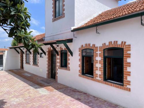 an exterior view of a white building with brick accents at Casa Luis Pato in Óis do Bairro