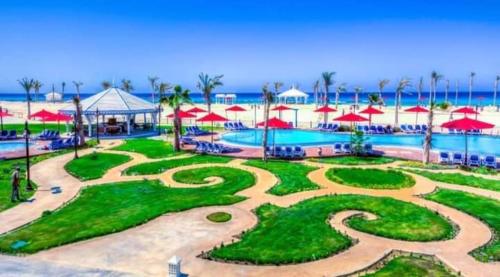 un resort con piscina con ombrelloni rossi di MASR Chalet - Porto Matrouh a Marsa Matruh