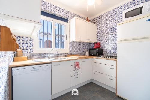 a kitchen with white cabinets and blue tiles at Mediterranean Way - El Patio in Vilafortuny