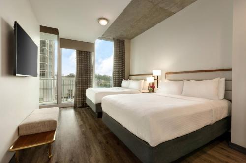 2 Betten in einem Hotelzimmer mit einem großen Fenster in der Unterkunft Twelve Midtown, Marriott Autograph Collection in Atlanta