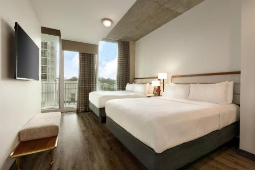 two beds in a hotel room with a large window at Twelve Midtown, Autograph Collection in Atlanta