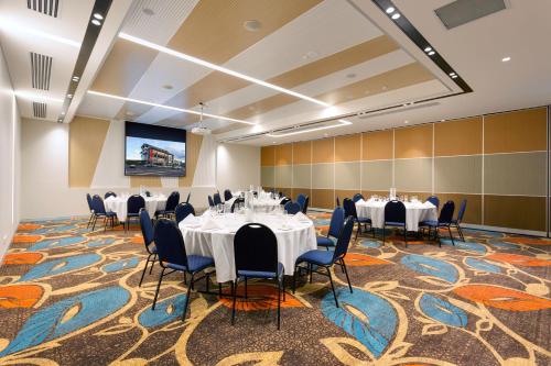 una sala de conferencias con mesas y sillas y una pantalla de proyección en Calamvale Hotel Suites and Conference Centre, en Brisbane
