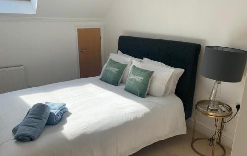 Un dormitorio con una cama blanca con almohadas verdes y blancas en Addlestone - Large Stunning 2 bed room Apartment, en Addlestone