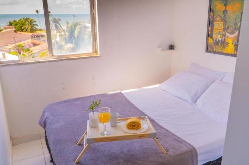 a bed with a tray with two glasses of orange juice at apartamento vista mar 2 quartos estacionamento gratis Netflix e self check in in Maceió