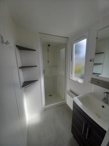 a white bathroom with a sink and a shower at LOCIMAD in Litteau