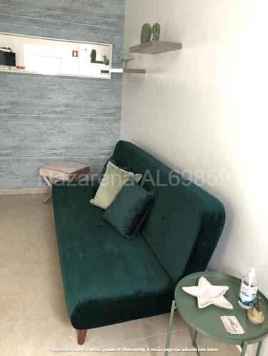 een woonkamer met een groene bank en een tafel bij Nazarena in Nazaré