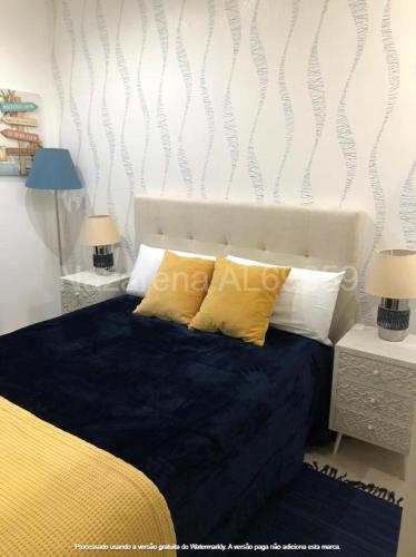 um quarto com uma cama com almofadas amarelas e brancas em Nazarena na Nazaré