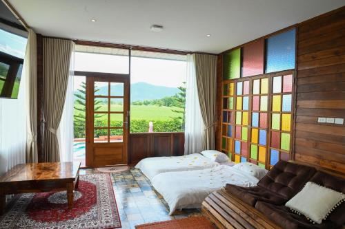 a bedroom with a bed and a couch and a window at DooNa Resort แลภูดูนา in Ban San Pa Sak