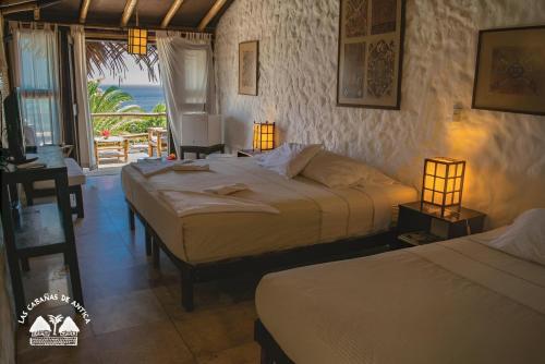 a bedroom with two beds and a view of the ocean at Las Cabañas de Antica in Vichayito
