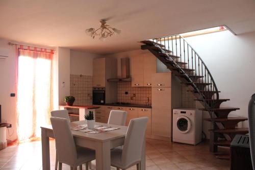 a kitchen and dining room with a table and a spiral staircase at La collina degli ulivi in Conocchia