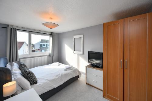 Dormitorio pequeño con cama y TV en Links Golf Villa, en Troon