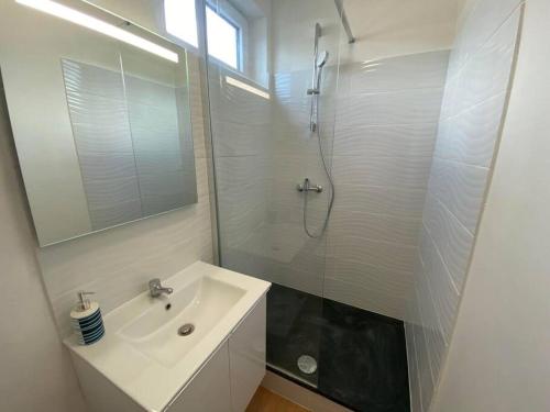 ein weißes Bad mit einem Waschbecken und einer Dusche in der Unterkunft Appartement du bonheur ! Av de la Mer in Saint-Jean-de-Monts