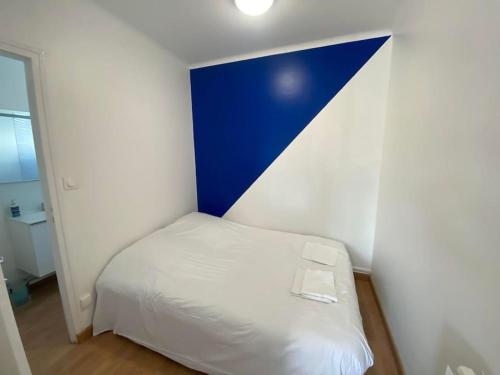 ein kleines Schlafzimmer mit einem weißen Bett und einem blauen Kopfteil in der Unterkunft Appartement du bonheur ! Av de la Mer in Saint-Jean-de-Monts