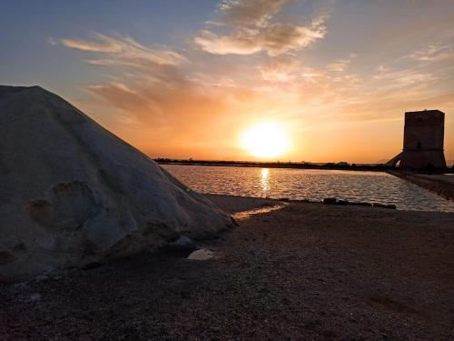 a sunset over a body of water with a large rock at Casale Sammartano Apartments in Ummari