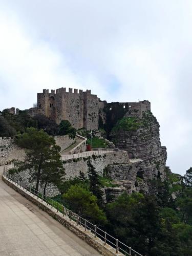 a castle on top of a mountain with trees at Casale Sammartano Apartments in Ummari
