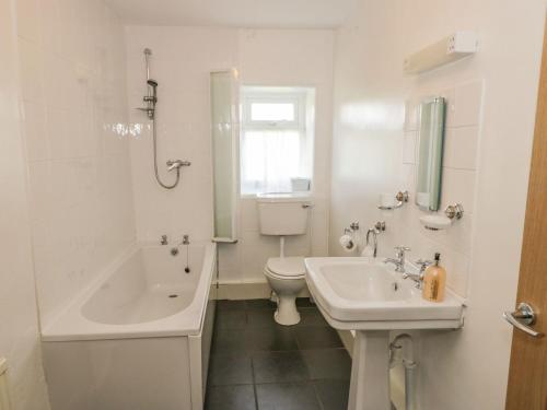 baño blanco con lavabo, bañera y aseo en The Hayloft en Ripon