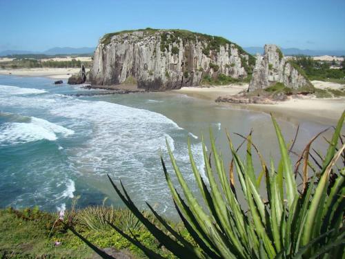 - une vue sur une plage avec une grande formation rocheuse dans l'établissement Loft Premium Torres RS, à Torres