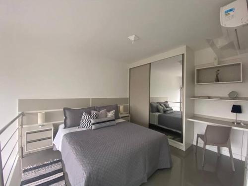 1 dormitorio con 1 cama grande y espejo en Loft Premium Torres RS, en Torres