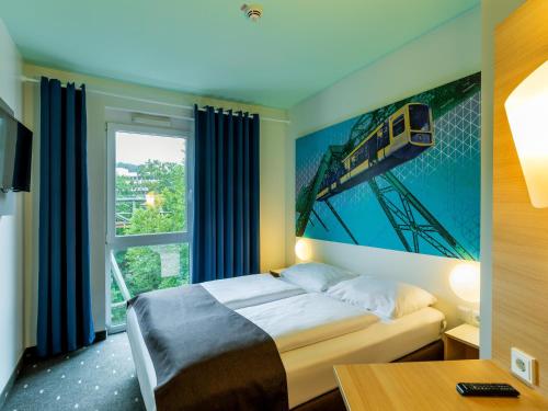 a bedroom with a bed with a train painting on the wall at B&B HOTEL Wuppertal City-Süd in Wuppertal