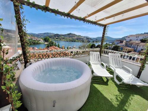 a hot tub on a balcony with chairs and a view at Stone House Entre os Rios in Entre-os-Rios