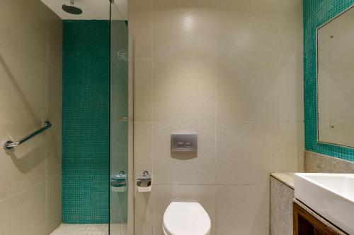 a bathroom with a shower with a toilet and a sink at Protea Hotel by Marriott Benin City Select Emotan in Benin City