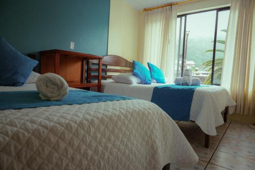 a hotel room with two beds and a window at Hostal CañaLimeña in Baños