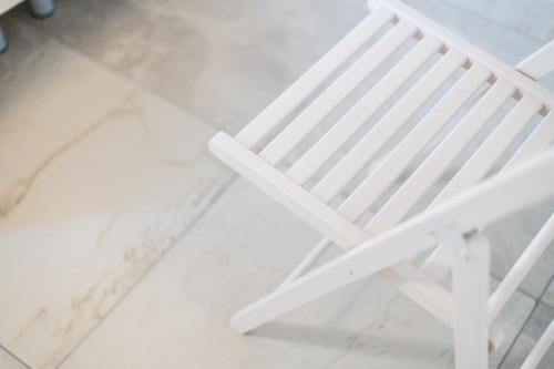 a white plastic chair sitting on a tiled floor at R&B al lago in Domaso