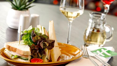 a sandwich and salad on a plate with a glass of wine at Holiday Inn Dresden - Am Zwinger by IHG in Dresden