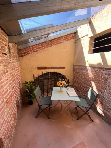 a patio with a table and chairs in front of a brick wall at Tuscany Experience BnB in Foiano della Chiana