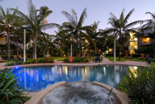 a large swimming pool with palm trees in a resort at Cairns Beach Resort in Cairns