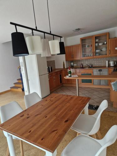 - une cuisine avec une table en bois et des chaises blanches dans l'établissement Haus in Bad Vilbel Messe Festhalle Hund, à Bad Vilbel