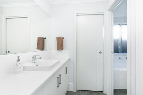 a white bathroom with a sink and a mirror at 3bedroom Modern Home in Mt Barker, 8km to Hahndorf in Mount Barker