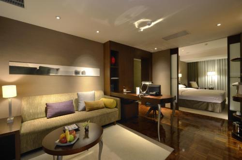 a hotel room with a couch and a bed and a desk at les suites taipei ching cheng in Taipei