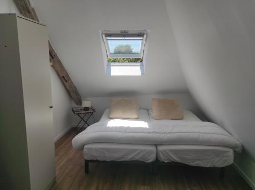 een bed in een kleine kamer met een raam bij gites de terophey & kena in Thiberville