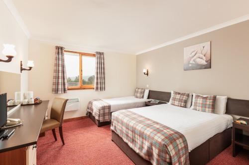 ニュートンモアにあるHighlander Hotel ‘A Bespoke Hotel’のベッド2台とデスクが備わるホテルルームです。