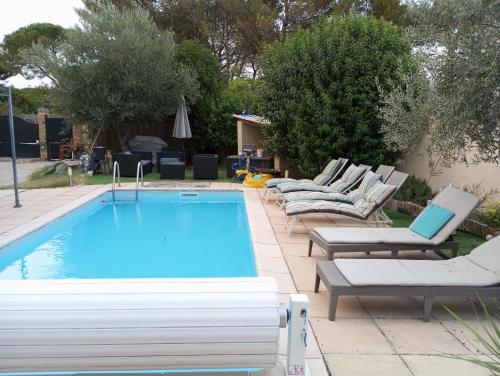 a swimming pool with lounge chairs and a lap poolvisor at Chez Mamiyo in Gallargues-Le-Montueux