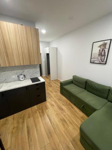 a living room with a green couch and a kitchen at Airport Apartment View Self Check-In Free parking in Vilnius