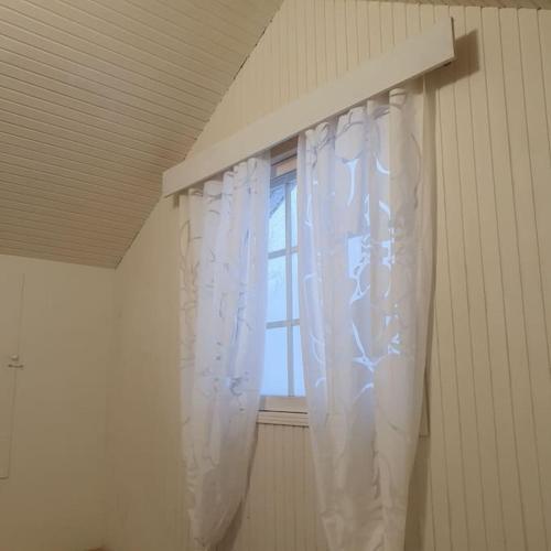 una ventana con una cortina blanca en una habitación en Yösija luonnon kupeessa, en Kuhmo