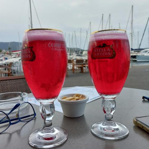 deux verres de liquide rouge assis sur une table dans l'établissement Bel appartement 2 chambres mer 400m clim, à Cavalaire-sur-Mer