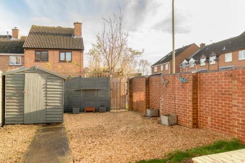 a building in a yard next to a brick wall at Modern 2 Bed Home Close To Village Centre in Kidlington