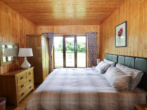 a bedroom with a large bed and a window at Barn Shelley Lodge in Copplestone