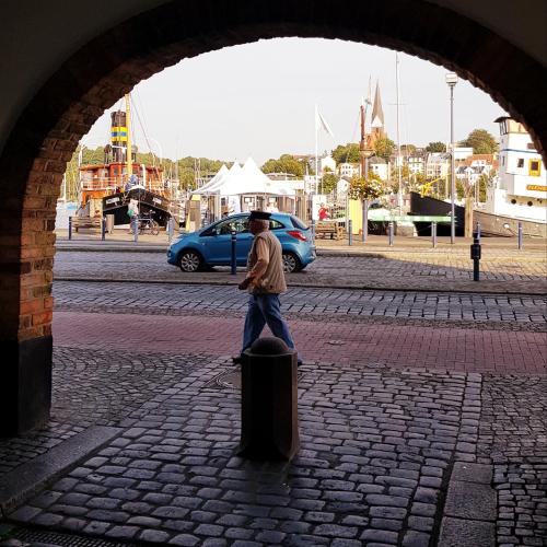 un homme marchant dans une rue avec une valise dans l'établissement Koje Sansibar, à Flensbourg