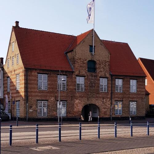 un grand bâtiment en briques avec un drapeau devant lui dans l'établissement Koje Sansibar, à Flensbourg