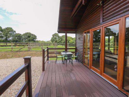 a wooden deck with a table and chairs on it at Barn Shelley Lodge in Copplestone