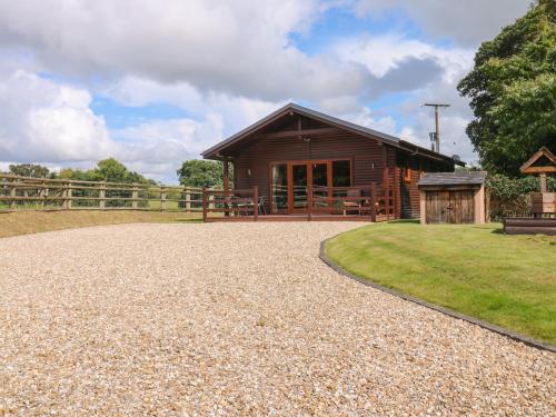 a log cabin with a gravel driveway in front of it at Barn Shelley Lodge in Copplestone