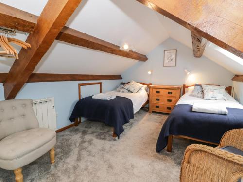 a attic bedroom with two beds and a chair at Garth Craig in Porthmadog