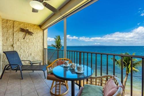 a balcony with a table and chairs and the ocean at KIHEI BEACH, #507 condo in Kihei