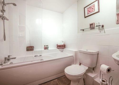a bathroom with a toilet and a tub and a sink at 2 Bed Charming Corner Position Apartment in Kidlington